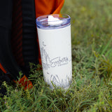 Ember Style Petal Tumbler standing in tall grass beside an orange backpack