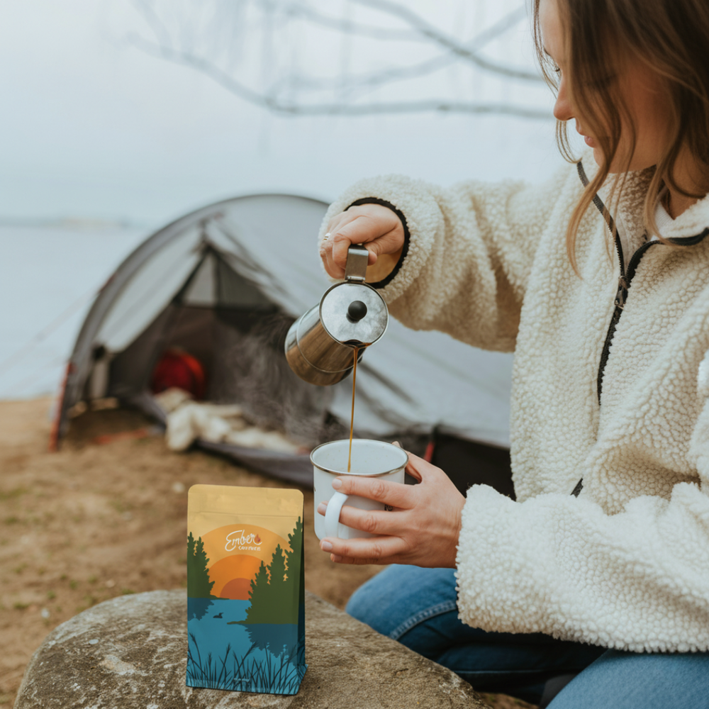 Pouring Ember Coffee at a lakeside campsite, lifestyle