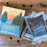 Ember Coffee Single Origin Box beside three 2 oz whole bean sample bags