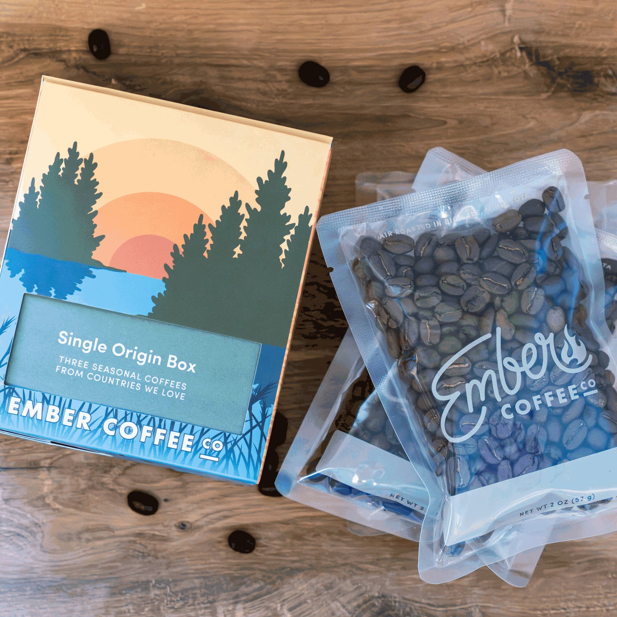 Ember Coffee Single Origin Box beside three 2 oz whole bean sample bags