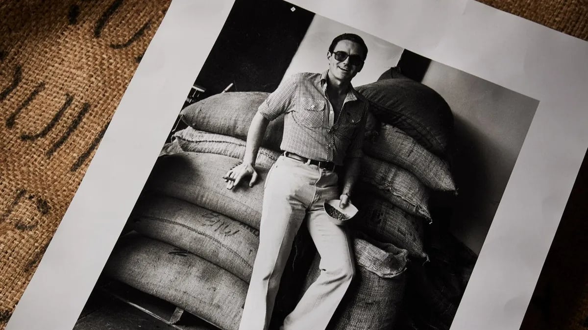 Coffee roaster standing beside stacked burlap sacks