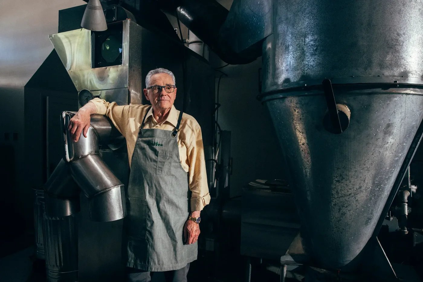 Coffee roaster standing beside roasting equipment